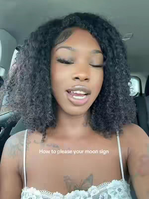 A woman with curly dark hair is shown in a car, looking towards the camera with her eyes closed and mouth open. The image is lit with soft, natural light. Text overlay says "How to please your moon sign".