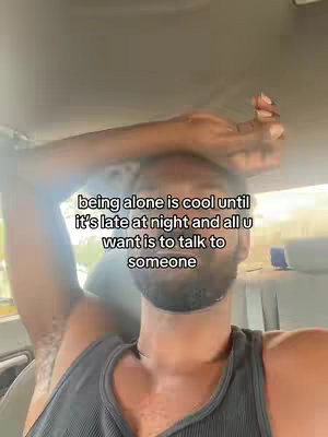 A selfie-style shot taken from inside a car, featuring a man in a gray tank top as the central focus. He raises one arm towards his head, partially obscuring his face. The background subtly shows car interiors, with a glimpse of the outside environment in the upper right corner. Text is overlaid on the image.