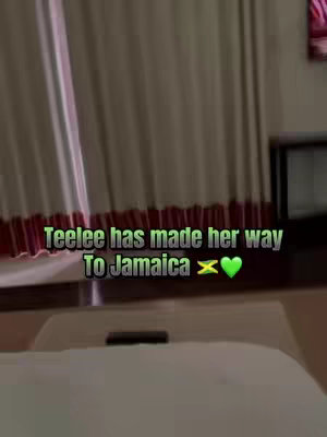 The cover image shows a dim room interior with a bed in the foreground, curtains and a window are visible in the background along with some furniture. Text is overlaid across the lower portion with the words 'Teelee has made her way to Jamaica' in a neon green and white font with some emojis.