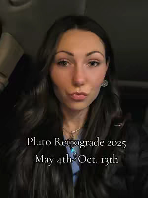 A selfie-style shot featuring a woman with long dark hair gazing at the camera. Her lips are slightly pursed. Text overlay indicates the video's subject: "Pluto Retrograde 2025 May 4th-Oct. 13th". The background is dark.