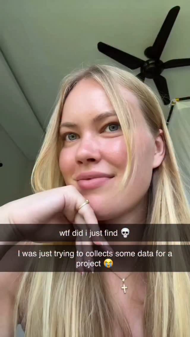 A close-up shot of a young woman with blonde hair and blue eyes, looking slightly to the side with a subtle smile. She is holding her hand near her face. Text overlays are present at the bottom. The background shows a ceiling and a ceiling fan.