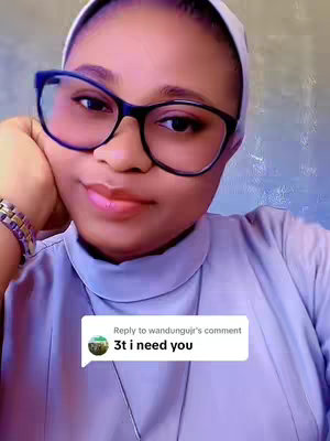 A close-up shot featuring a woman with fair skin, wearing large black-framed glasses and a light purple turtleneck. She has a white headscarf in place and is wearing a gold and purple bracelet. A speech bubble in the corner reads a message of '3t i need you'. The background is a light blue.