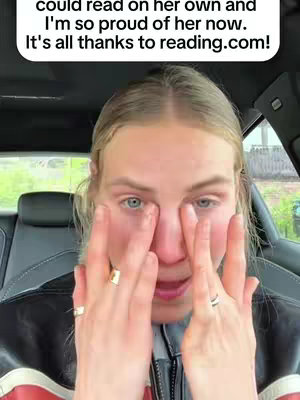 The cover image features a close-up shot of a woman inside a car. She has blonde hair and is wearing a black jacket with red and white stripes. Her hands are raised towards her face. The background shows a glimpse of greenery outside the car window. The overall composition is a medium shot with a focus on the woman's expression.