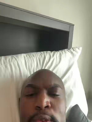 The cover image shows a close-up of a Black man lying on a white pillow, with a gray headboard in the background, creating a casual and intimate setting.