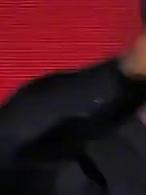 An out-of-focus image with a red background and a portion of a person in dark clothing, the person is out-of-focus.