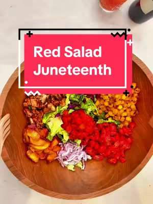 A top-down shot of a wooden bowl filled with a colorful salad. The salad is segmented into sections, including red beans, cornbread croutons, red onion, tomatoes, grilled peaches, fire roasted peppers, and more. A red rectangular overlay with white text that reads "Red Salad Juneteenth" is superimposed at the top center of the image, which also contains two wooden spoons.