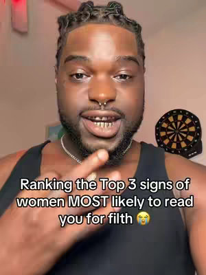 A man with dark skin, braided hair, a septum piercing, and gold teeth smiles into the camera. Text overlays his chest. A dartboard is partially visible in the background.