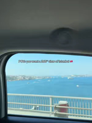 A view from inside a car window looking out at a cityscape and a body of water, likely a sea or large lake. The sky is bright blue. Text overlay reads “POV: you want a 360° view of Istanbul 🇹🇷”.