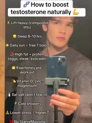A young man is holding his phone in front of him to record a video. Text overlays are on the top and left side of the image. The background is slightly blurred. The man is wearing a dark grey shirt.