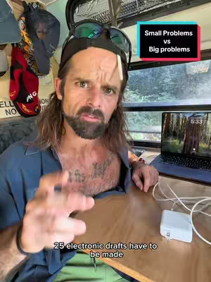 A man is sitting at a table inside of what appears to be a van. The man is pointing towards camera with a focused look, the background reveals more of the van's interior. Text overlays present on the cover image.