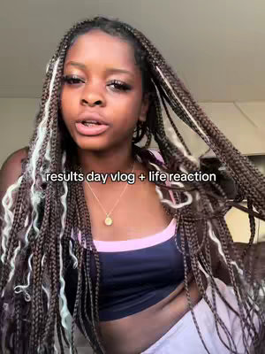 A young woman with long, braided hair, some sections highlighted in white, is looking directly at the camera. She's wearing a casual top, a necklace, and her face is well-lit. The words 'results day vlog + life reaction' are overlaid on the image toward the bottom.