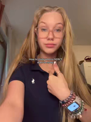 A young woman with long blonde hair and glasses is pointing at herself with a thumbs-up. The text overlay reads: 'How to study when u DON'T want to study'. She is wearing a dark blue polo shirt and a watch with several bracelets on her wrist.