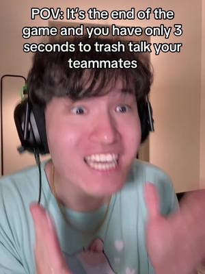 A close-up photo of a young man with dark hair and a bright, energetic expression. He's wearing a light blue t-shirt and black and silver headphones. His eyes are wide, and he's smiling widely, showing his teeth. The background is blurry, suggesting an indoor setting.
