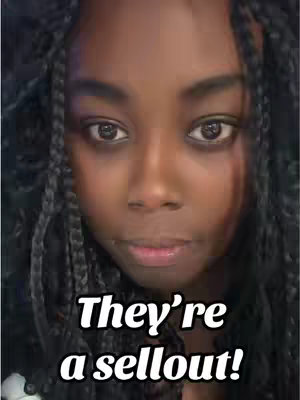 A close-up shot of a woman with dark skin and braided hair. The background is blurred, drawing focus to her face. Text overlay at the bottom reads "They're a sellout!"