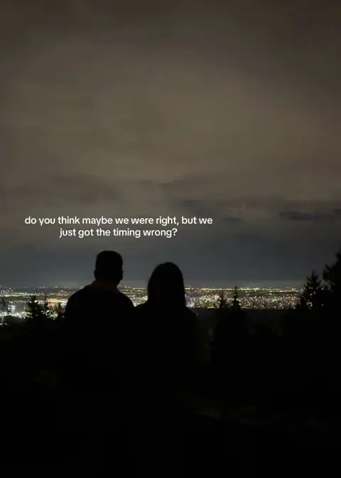 Silhouette of a couple standing on a hilltop overlooking a city at night, with text added as an overlay.