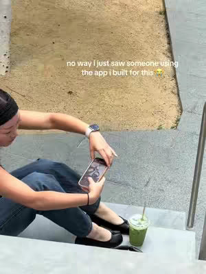 A person is sitting on stairs, looking at their phone and a matcha drink is to the side. The caption includes text overlay and is about an app that the person made.