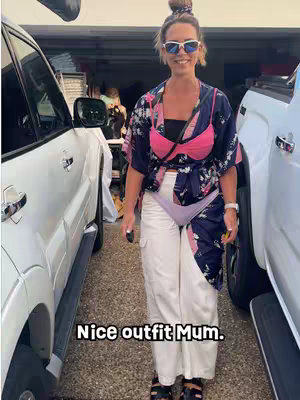 A woman in a mismatched outfit stands between two white SUVs. The hook text is overlayed at the bottom of the screen.  She is smiling and wearing sunglasses.