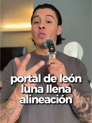 A man with tattoos on his forearm stands with a microphone in his hand, making a hand gesture. Overlaid on the image are the words 'portal de león luna llena alineación' in white block letters.