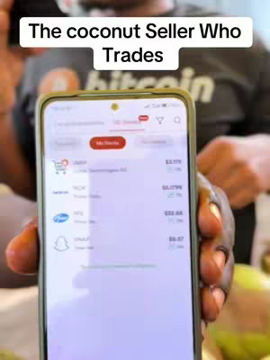 A person holds a smartphone displaying a financial app interface, presumably showing stock or cryptocurrency data. The person is out of focus, but the phone screen dominates the shot, with text overlayed at the top. The background behind the phone is slightly blurry.