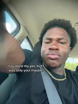 A young Black man is shown in a car, facing the camera. He has short, textured hair and is wearing a black shirt and a gold chain. The car interior is visible, and the text overlay at the bottom reads, "You were my yes, but I was only your maybe."