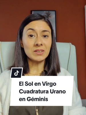 A woman with brown hair is centered in the frame, facing the camera. She's wearing a white sweater over a brown top and sitting in a light green chair. Behind her are orange walls, with what seems a framed picture on the right. A white box with black text overlays the bottom, including the word "El Sol en Virgo". A Tik-Tok logo is in the lower-left corner.