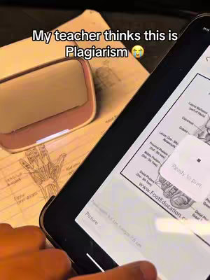 An angled shot featuring a hand holding a tablet displaying a document with diagrams of the foot. A small device, possibly a scanner, sits next to the tablet, and a sheet of paper with a drawing of a hand is visible in the background.