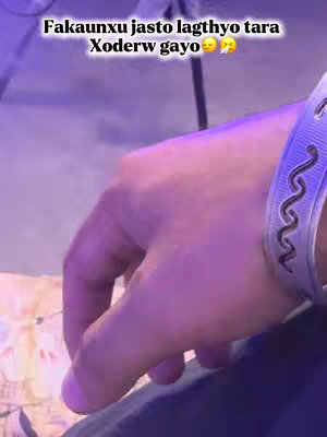 The image shows a close-up of a hand, likely a wrist, with a silver bracelet. Above the hand is a text overlay written in a script. The lighting is dim with a purple hue, and the overall aesthetic hints at a contemplative or regretful mood.
