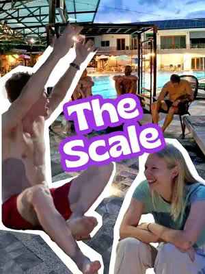The cover image is a vibrant outdoor shot at a pool-side setting, featuring two main individuals and several other people blurred in the background. The central focus is a man in red shorts reaching upwards excitedly and a woman, on the right, smiling and looking at him. Above them, in a vibrant, cloud-like shape, is the text overlay "The Scale". The background includes a pool and what looks like a semi outdoor bar, with other blurred individuals.
