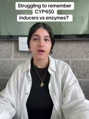 A woman with dark hair is centered, looking directly at the camera. She wears a black top under a white shirt and a necklace. Text overlays at the top, written in a white font, reads 'Struggling to remember CYP450 inducers vs enzymes?' The background is a light gray cinder block wall.