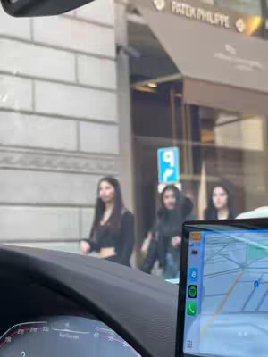 The cover image shows a view from inside a car, with three women walking on the sidewalk in the background. Buildings, and a street sign are also visible.