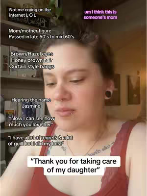 A woman is centered in a selfie-style video, her face framed by honey-brown hair and curtain-style bangs. She has brown/hazel eyes and a small nose ring. A visible tattoo is present on the upper chest and the woman is wearing a red top. Text overlays mention aspects such as “Mom/mother figure”, which is the main topic of the video, and the main text overlay at the bottom saying “Thank you for taking care of my daughter”.