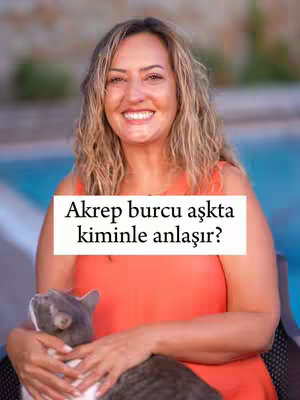 A woman with long blonde hair smiles while holding a gray cat. She's wearing an orange top. A text overlay reads, 'Akrep burcu aşkta kiminle anlaşır?' (Who does Scorpio get along with in love?) The background is blurred, featuring a pool.