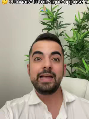 A man with dark hair and a trimmed beard is centered in the frame, looking directly at the camera with a surprised expression. Above his head, there's a text overlay, and in the background, a lush green plant adds a natural element to the scene.