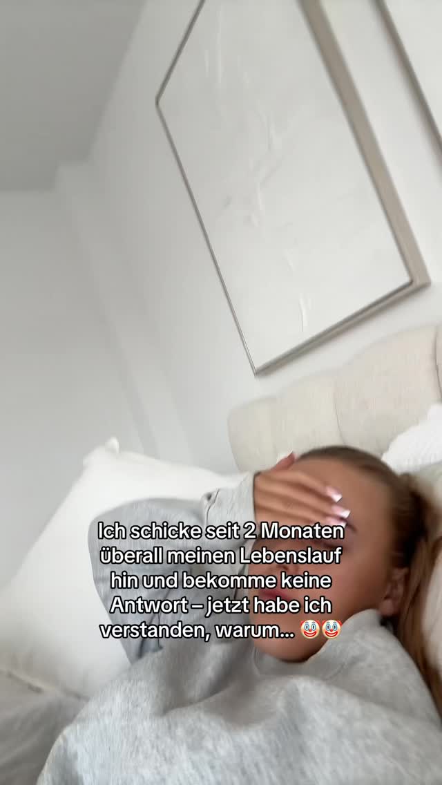The image is a close-up shot of a person lying in bed, with their face partially covered. The person is wearing a grey hoodie. Text overlay is on the bottom left.
