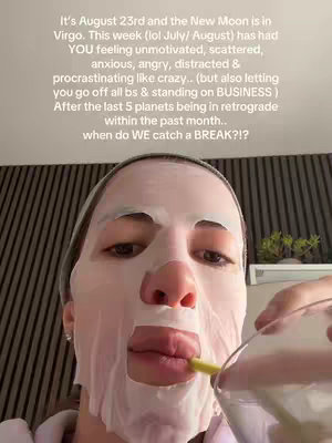A selfie-style shot featuring a person's face covered by a white sheet mask, with visible eyes, nose and lips, and a glass in their hand with a drinking straw in their mouth.