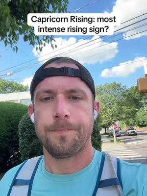 The cover image is a selfie of a man in a blue shirt, black cap, and white earbuds, set against the backdrop of a sunny day and a suburban street. Overhead, a text overlay reads, "Capricorn Rising: most intense rising sign?"