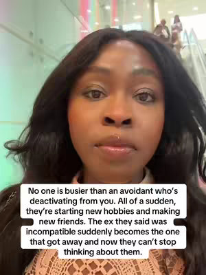 A medium shot focuses on a Black woman with dark, wavy hair and makeup, looking directly at the camera. She is wearing a light-colored top with a delicate pattern. Behind her, an escalator leads up, and faint figures of people are visible. A text overlay in a white box occupies the lower portion of the frame, presenting a statement about avoidant behavior in relationships.
