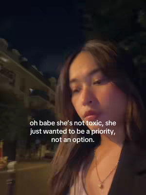 A nighttime selfie of a woman with brown hair. The foreground features the woman's face, with the text overlayed on the lower portion of the image. In the background, there are partially visible buildings and streetlights.