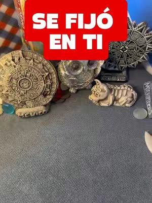 The cover image showcases a collection of spiritual artifacts, including an Aztec calendar, a silver owl, and various figurines, all arranged on a gray surface. A red banner across the top displays Spanish text.