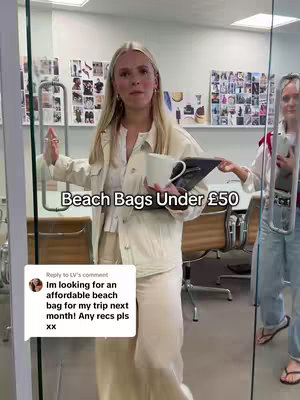 A woman stands in a brightly lit office setting, holding a mug and a laptop. Another person is partially visible on the right side, also holding a phone, behind a glass door. The overlay text reads 'Beach Bags Under £50'. A comment bubble at the bottom contains a question about affordable beach bag recommendations.