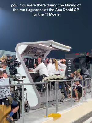 An image taken from the viewpoint of someone on set during a filming of the Abu Dhabi Grand Prix for the F1 movie. Several crew members are visible around a control unit as they work by screens.