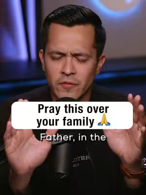A close-up shot of a man with short, dark hair and a serious expression. He is positioned in front of a blurred background, likely a studio setting due to the lighting. Overlayed on the image is a white rectangular element containing text, prompting the viewer to pray for their family, and is accompanied by a prayer hands emoji.