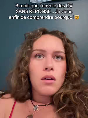 A selfie-style image shows a woman with curly hair looking directly at the camera with a surprised expression. She is wearing a red top and several necklaces. The background is a dark blue-green.