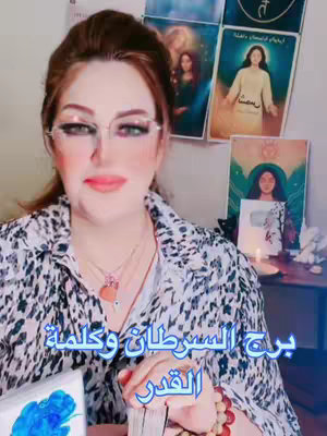 The cover image features a woman with long brown hair and glasses, wearing a patterned shirt. She is positioned in front of a backdrop of spiritual imagery, including tarot cards and posters with angelic figures. The text overlay is in Arabic.