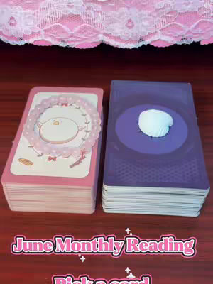 The cover image features two decks of tarot cards, one pink with a circular design and bracelet, and the other purple with a white seashell. The text overlay reads 'June Monthly Reading' and 'Pick a card'. The background has pink lace, and the scene is set on a wooden surface.