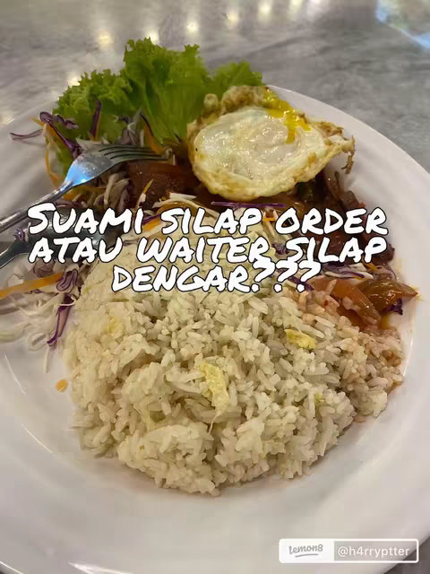 A plate of food, featuring a large portion of white rice is the main element, topped with a scattering of red-colored meat, a fried egg with a bright yellow yolk, and a garnish of shredded vegetables. A fork is placed on the upper left of the plate. Overlayed on the image is white text, set against a partial blurred background.