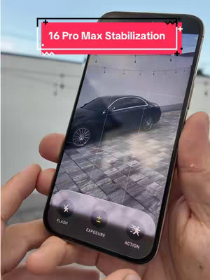 A person holding a smartphone displaying a car scene and the iPhone camera interface. A hook with the text '16 Pro Max Stabilization' is overlaid on the top. The person's hands are holding the phone, with focus on the screen.