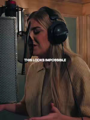 A woman with long blonde hair is in a recording studio, with a microphone in front of her mouth. The text overlay reads "THIS LOOKS IMPOSSIBLE".