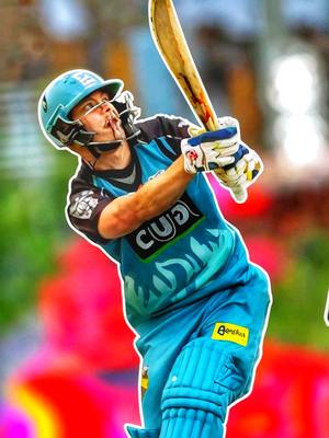 A dynamic, action-packed image of a cricket player in mid-swing. The player, dressed in a teal and black uniform with padding, is centrally positioned, swinging a cricket bat. The background is a blurred mix of red and green, possibly representing a stadium or outdoor setting. The overall composition emphasizes movement and energy.