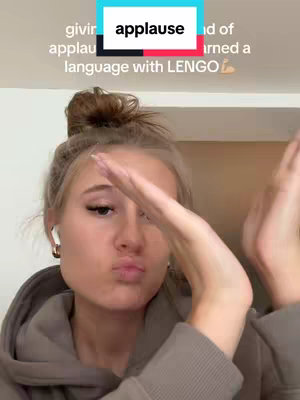 A selfie-style video cover with a young woman in a hoodie, making a kissing face with her lips and clapping her hands near her face. Text is overlaid in a rectangular box, centered at the top.